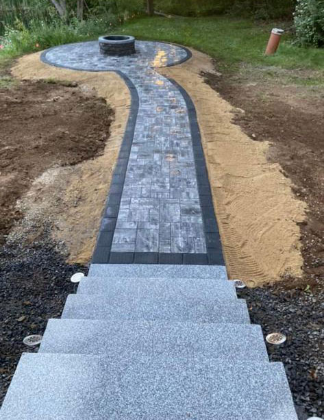 Charcoal-bordered paver walkway running from granite steps to a fire pit